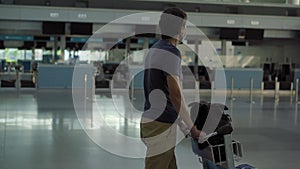 Man in mask at empty airport at check in in coronavirus quarantine isolation, returning home, flight cancellation