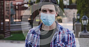 Man in mask and gloves holds last dollar in hands, is sad and looking at camera