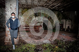 Man in the mask, leaning against a column of an abandoned ruin, symbol of sadnesss, desperation and fear of illness