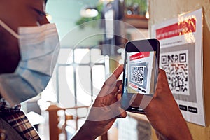 Man In Mask With Mobile Phone Checking Into Venue Scanning QR Code During Health Pandemic