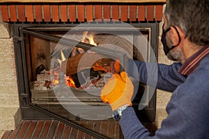 Man in mask puts log in burning fireplace