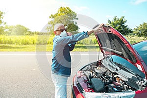 Man with mask talking on his cell phone with his car broken down