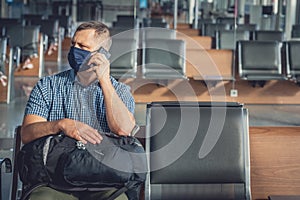 Man with a mask talking on mobile phone in airport lounge