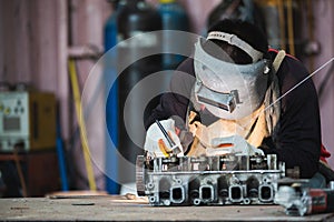 The man in the mask is welding metal with argon-arc photo