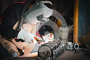 The man in the mask is welding metal with argon-arc