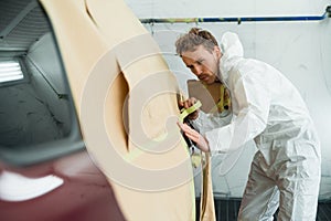 Man masking a car body before painting.