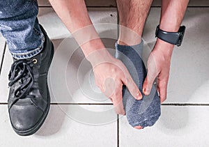 A man massages his foot with his hands.