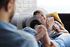 Man Massaging Girlfriend Feet On Sofa At Home