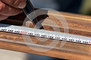 Man master builder measures metal with a working measuring tool, tape measure and marker in the hands of a worker