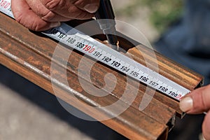 Man master builder measures metal with a working measuring tool, tape measure and marker in the hands of a worker