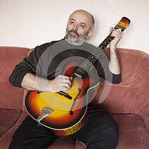 A man of mature years playing an acoustic guitar