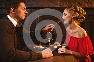 Man meals elegant woman in red dress in restaurant