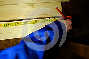 A man measures the boards with a tape measure