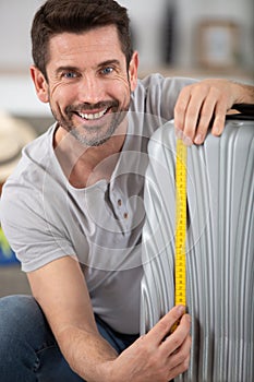 man measures lugagge to comply low cost airlines restrictions photo