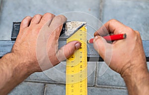 Man measures metal with a ruler for cutting
