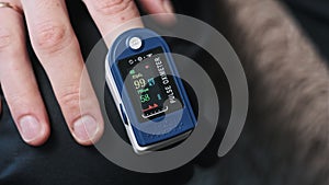 Man Measures Pulse and Oxygen Saturation with a Pulse Oximeter at Home.
