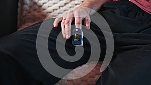 Man Measures Pulse and Oxygen Saturation with a Pulse Oximeter at Home.