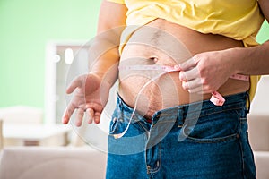 The man measuring body fat with tape measure in dieting concept