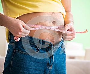 Man measuring body fat with tape measure in dieting concept