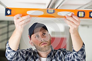 man measuring ceiling with sprit level