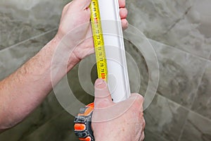 Man is measuring gypsum baseboard. Maintenance repair works renovation in the flat. Drywall panel