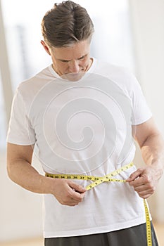 Man Measuring His Waist At Health Club