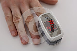 Man measuring oxygen level with modern fingertip pulse oximeter at white table, closeup