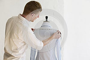 Man Measuring Shirt On Mannequin In Fashion Studio