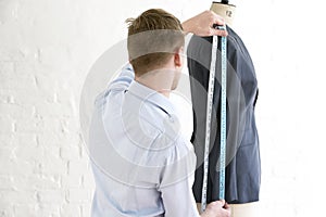 Man Measuring Suit On Dressmaker's Model In Studio