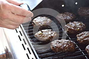 Man measuring temperature of burger cooking on the grill