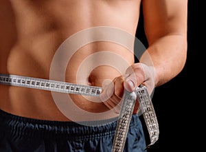 Man is measuring waist with centimeter tape