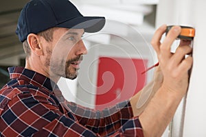 man measuring wall with tape measure