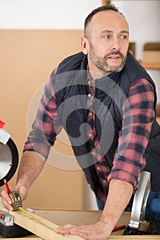 man measuring wood with tape measure