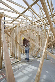 Man Measuring Wooden Beam In Framework