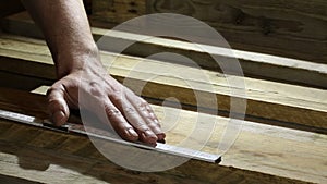 Man measuring wooden board with folding ruler in carpenters workshop