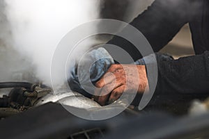 Man mechanic repair a smoking engine of his overheated car