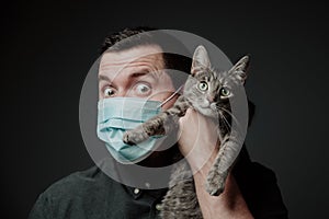 A man in a medical mask with a cat