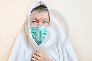 A man in a medical mask covered himself with a housecoat, self-isolation, quarantine, stay home