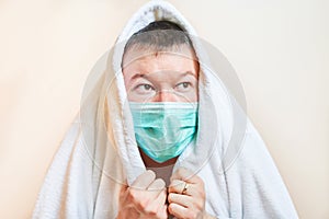 A man in a medical mask covered himself with a housecoat, self-isolation, quarantine, stay home, fear