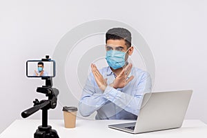 Man in medical mask gesturing stop with crossed hands, warning about coronavirus outbreak, dangerous contagious disease
