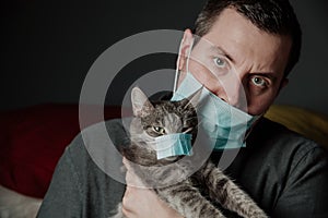 A man in a medical mask with a grey cat in medical mask