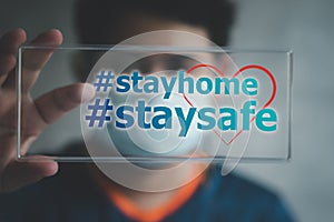 Man in medical mask  holding sign with stay home and stay safe text. Social media campaign for coronavirus prevention