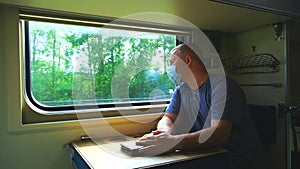 A man in a medical mask rides by the window on a train