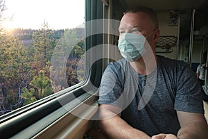 A man in a medical mask rides by the window on a train