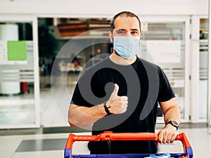 Man in medical mask shopping at supermarket with thumb up