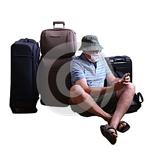 man in a medical mask with a smartphone in hand and suitcases at the airport