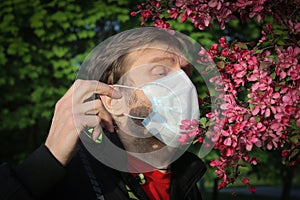 A man in a medical mask sneezes from pollen photo