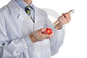 Man in medical white coat makes an injection to red ripe tomato