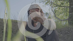 A man in medieval peasant clothing rests under a tree.