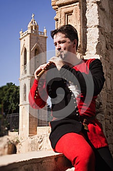 Man in a medieval suit plays a flute